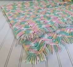 a multicolored crocheted blanket laying on top of a white wooden floor