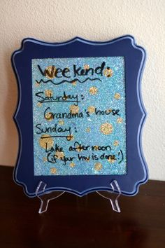 a blue frame with words on it sitting on top of a wooden table next to a wall