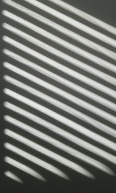 the shadow of a window on a wall is cast by light coming from it's blinds