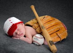 a baby is laying next to a baseball and glove