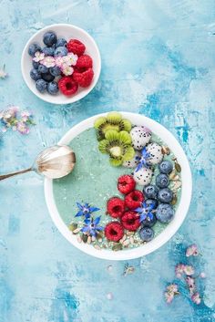 two bowls filled with berries, kiwis and strawberries next to each other