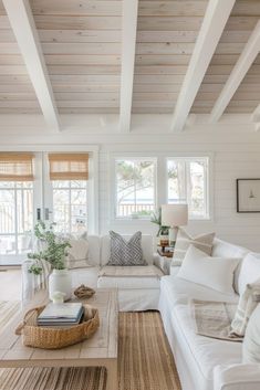 a living room with white couches and pillows