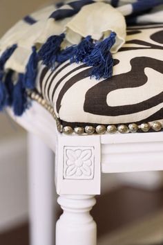 a close up of a chair with a pillow on it's back and some beads around the legs