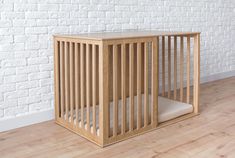 a small wooden crate sitting on top of a hard wood floor next to a white brick wall