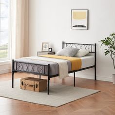 a bed sitting on top of a hard wood floor next to a potted plant