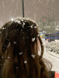 the back of a woman's head with snow falling on her