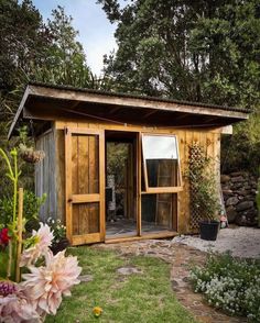 a small wooden shed sitting on top of a lush green field