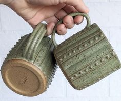 a hand holding a green ceramic watering can