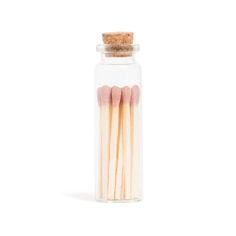 matches are in a glass jar on a white background with a cork lid and two small matches sticking out of it