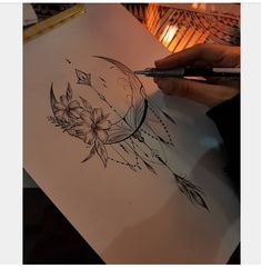 a person is drawing on paper with a pen and inkbrush in their hand, next to a lit candle