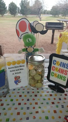 a table topped with coins next to a glass jar filled with coins and a stuffed animal