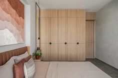 a bedroom with wooden closets and white carpeted flooring in front of a large painting on the wall