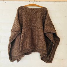 a brown sweater hanging on a white brick wall