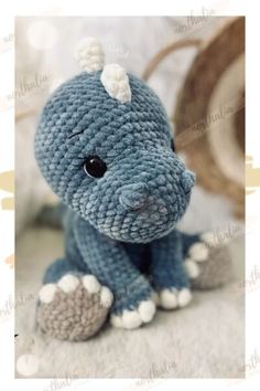 a crocheted blue stuffed animal sitting on top of a white blanket