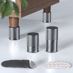 a set of four silver canisters sitting next to each other on a white floor