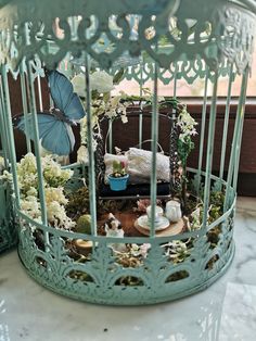 a blue birdcage filled with flowers and other things sitting on top of a table