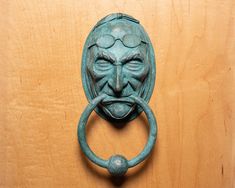 a door handle with a face on it and a ring in front of it that is attached to a wooden wall