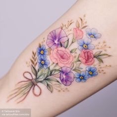 a woman's arm with flowers painted on it and a bow around the wrist