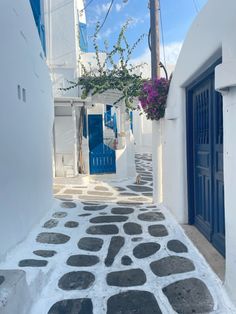 an alley way with white buildings and blue doors on both sides, in the town of mykonos