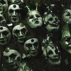 a group of masks with faces painted black and white, all lined up in rows