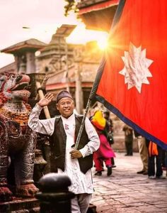 a man holding a canadian flag in front of a temple with other people around him