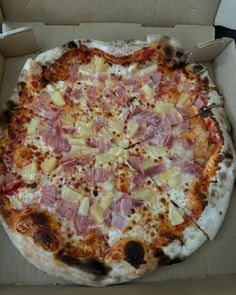 a pizza with ham, pineapple and cheese in a box