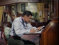 a man sitting at a desk with a laptop in front of him and writing on a piece of paper