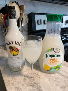 a bottle of tropicana next to a glass filled with liquid on a kitchen counter