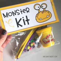 a hand holding a yellow monster kit with beads and candy in it's pouch