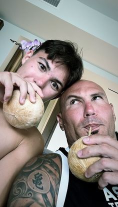 a man and woman eating bread together in front of a mirror with tattoos on their arms