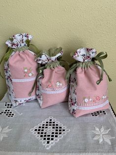 three pink bags sitting on top of a table next to a white lace doily