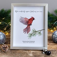 a red bird sitting on top of a wooden table next to christmas decorations and pine cones