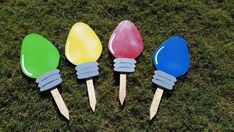 four colorful plastic spoons sitting in the grass