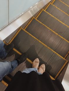 two people sitting on an escalator with their feet up and one person standing next to them