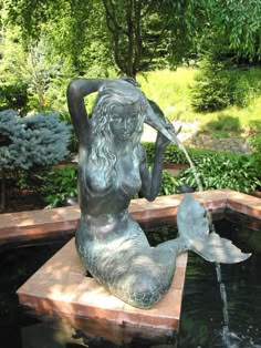 a statue of a mermaid sitting on top of a fountain