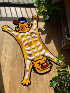 a yellow rug with a cartoon cat on the floor next to a potted plant