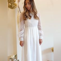 a woman wearing a white dress standing in front of a wall