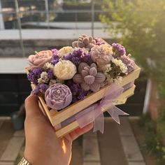 a person holding a wooden box with flowers in it