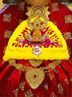 an idol is displayed in the middle of a red and yellow cloth with gold decorations