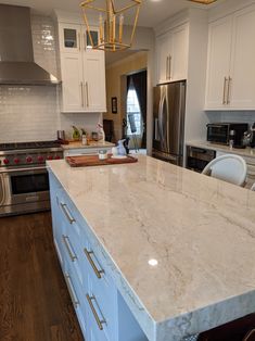 a large kitchen with white cabinets and marble counter tops, an island in the middle