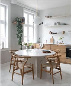 a white table with four chairs around it in a kitchen next to a potted plant