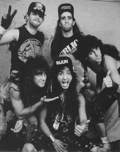 an old black and white photo of five people posing for the camera with their hands in the air