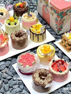 there are many different cakes on the trays and one is decorated with fruit,