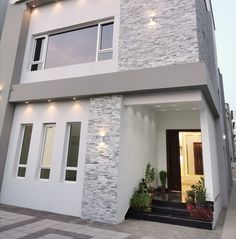 the front of a modern house with white and grey stonework on the facade, door and windows