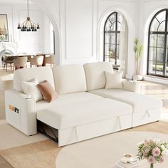 a living room filled with white furniture and lots of windows in the wall behind it