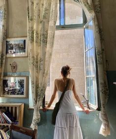 a woman standing in front of a window looking out