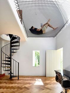 a person is hanging upside down from the ceiling in a room with wood flooring