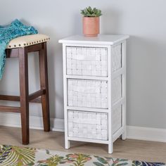 a white cabinet with three drawers next to a stool