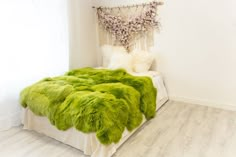 a bedroom with white walls and green fur on the bed