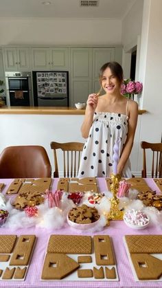 a woman standing in front of a table filled with cookies